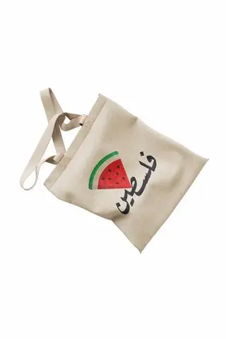 حقيبة قماشية بكلمة فلسطين وفوقها حز البطيخ